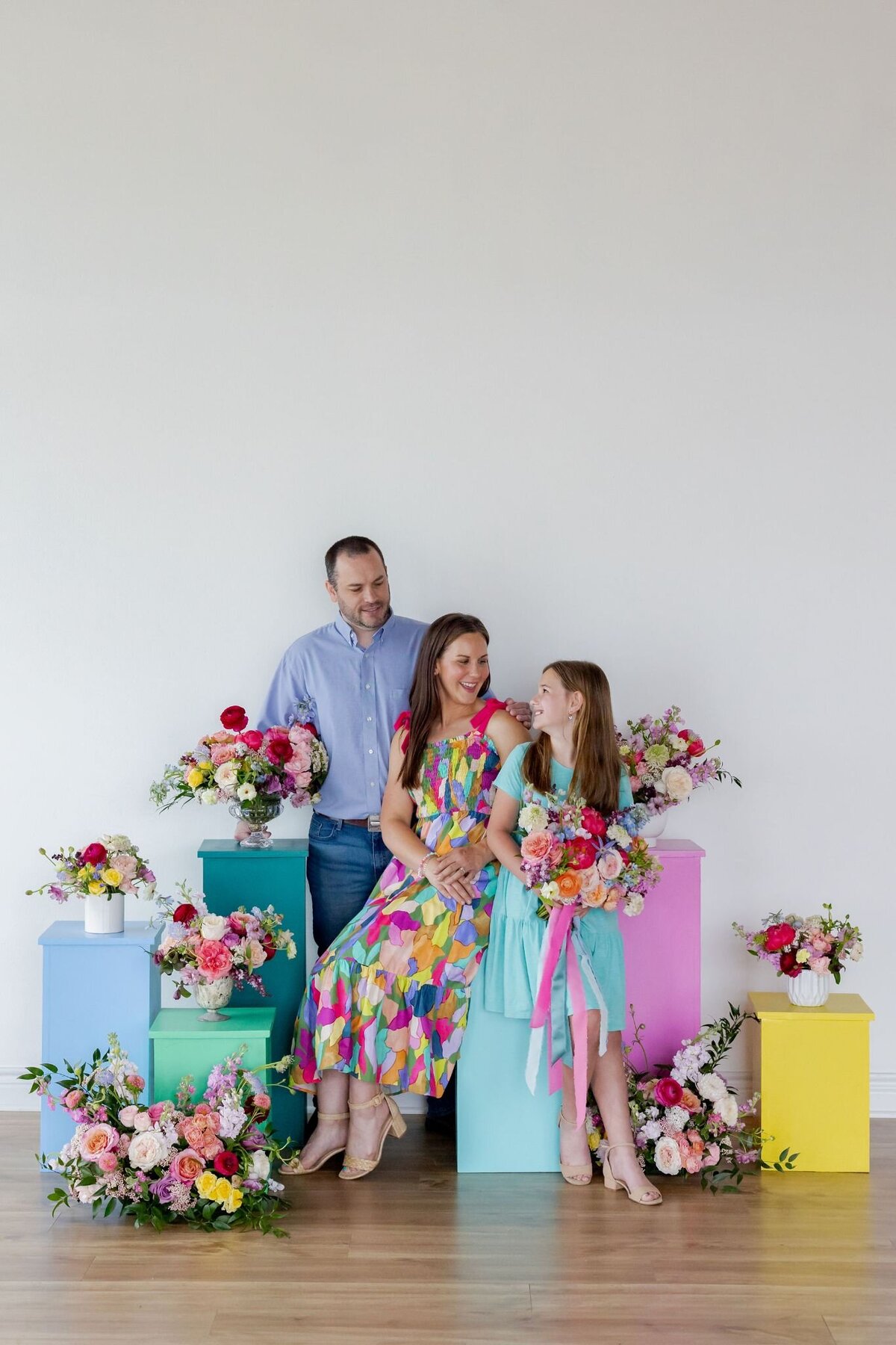 Tamara Menges and family surrounded by vibrant floral arrangements in studio, showcasing joyful garden-inspired wedding flowers.