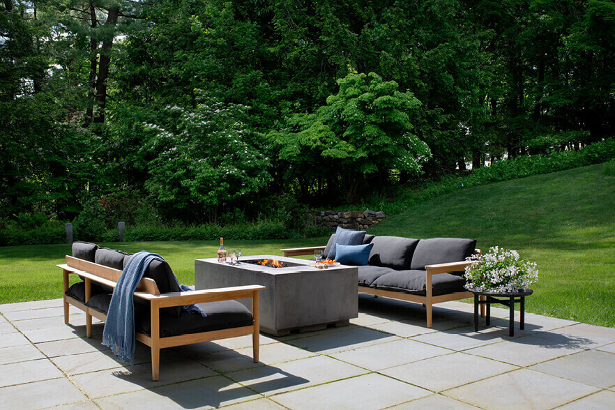 A firepit and teak sofas complete the new patio, with landscape design and modern furniture in Boston, creating a stylish and functional outdoor retreat.