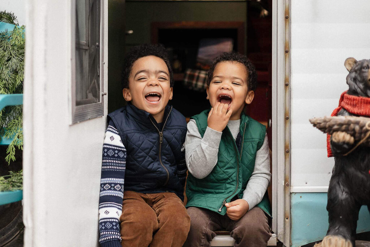 Brothers laughing in vintage camper at Breezewood Gardens in Chagrin Falls, Ohio. Joyful, candid Christmas photos.