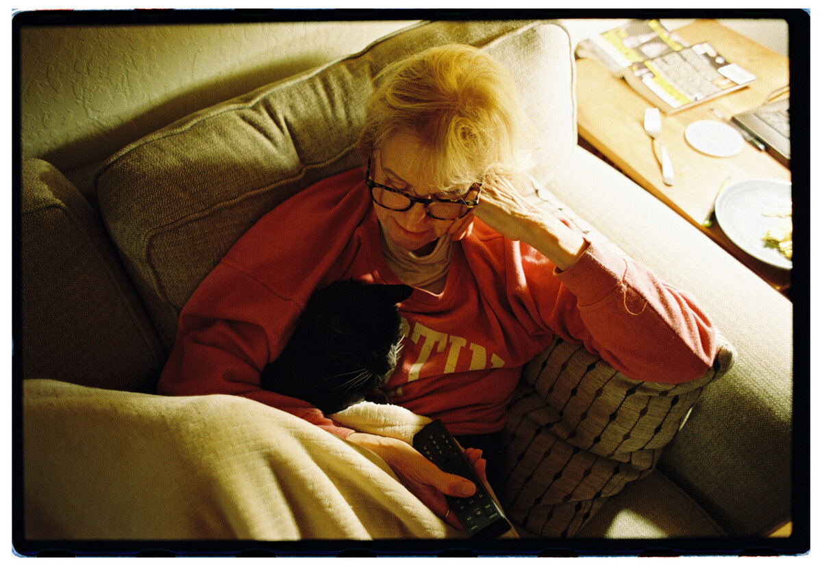 Older woman holding her cat, captured on film by Kate Winters Photography, showcasing an authentic and candid moment in Carmel, California.