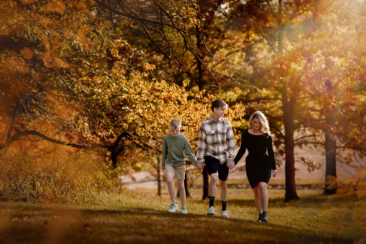 A girl and her 2 brothers walk through the fall colors