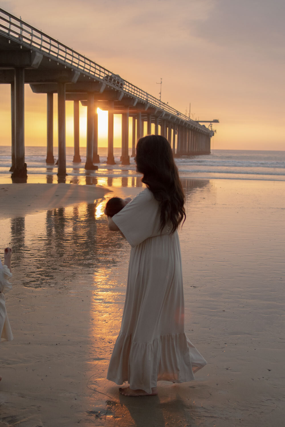 A woman holding a baby while watchintg the sunse