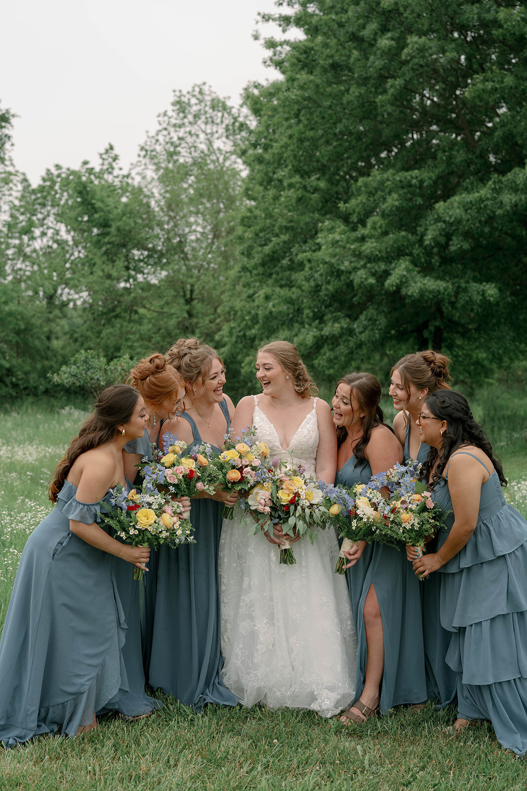 Candid photo of the bride and bridesmaids laughing together during wedding party portraits at Blue Heron Barn.