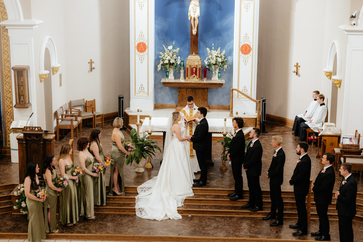 Bride and groom standing at the alter with their bridal party. 