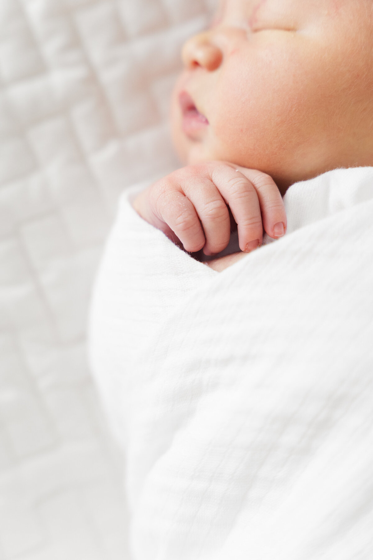 A closeup view of a swaddled newborn, peacefully resting