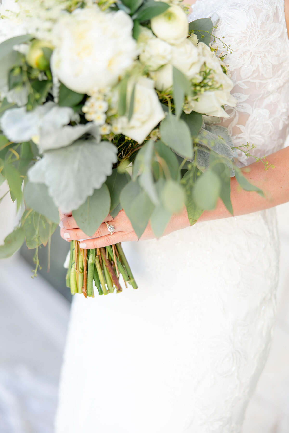 wedding ring in focus while bride holds white rose bouquet captured by wedding photographer in Texas