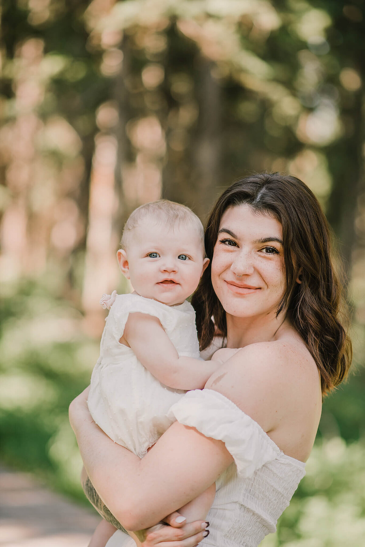 A close up image of a beautiful mother and daughter. Mom holds her daughter close while they both smile at the camera. Portrait by Brittany Danielle