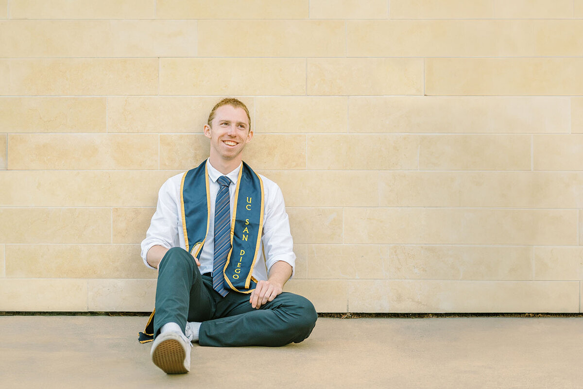 UCSD senior guy graduate leaning against a wall