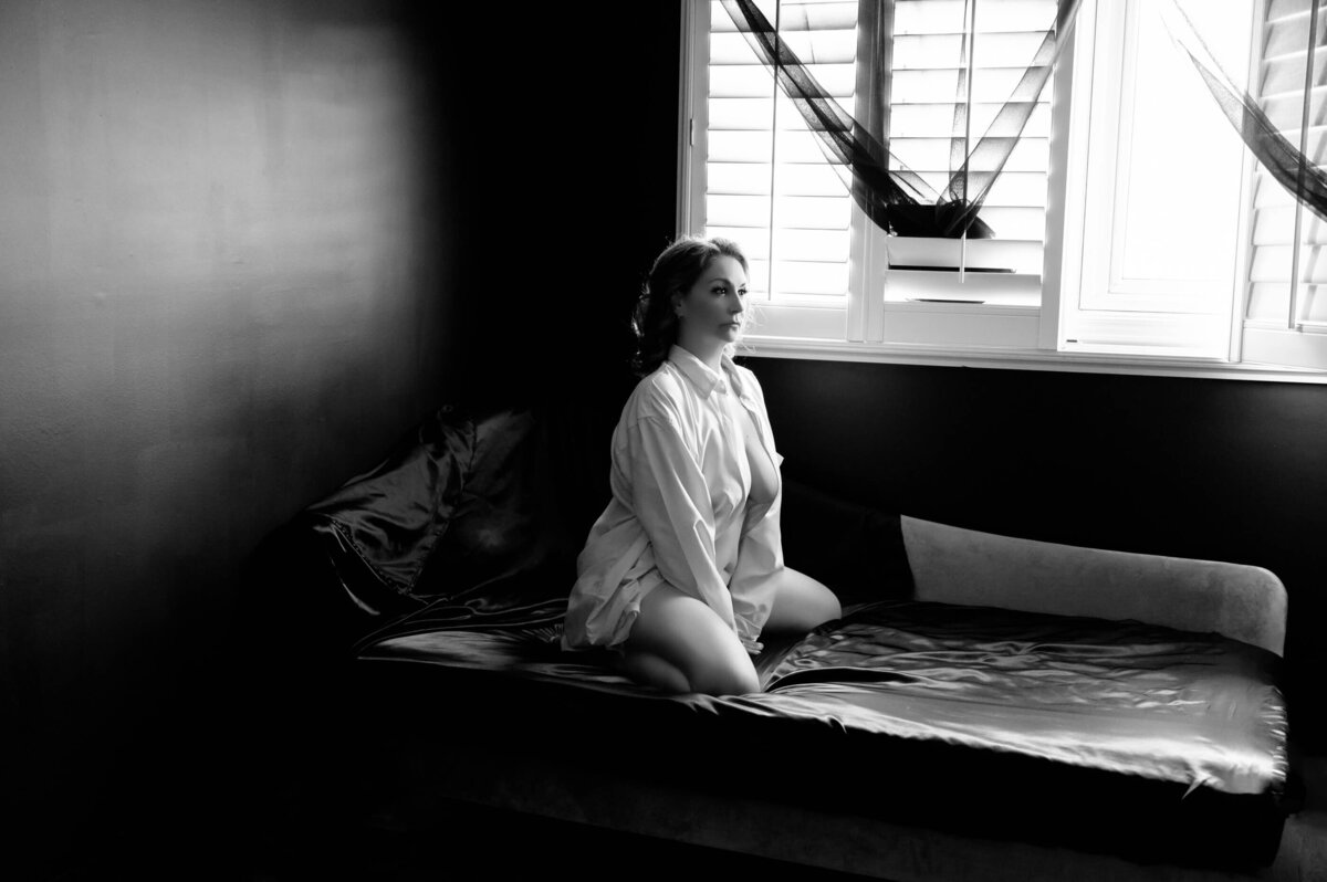 woman sitting on bed wearing a dress shirt in black and white
