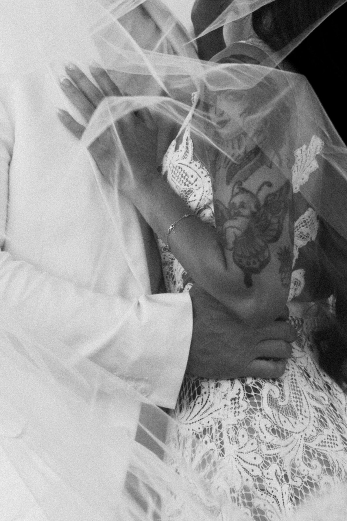 Close up of a bride with a lot of tattoos under a veil with the groom