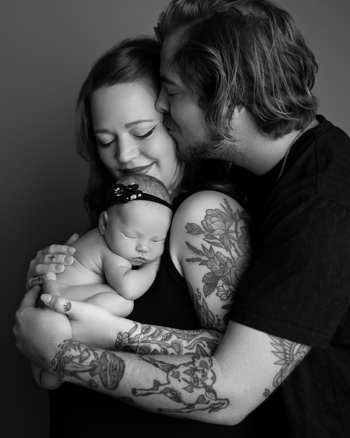 tattooed parents snuggling holding their newborn baby girl