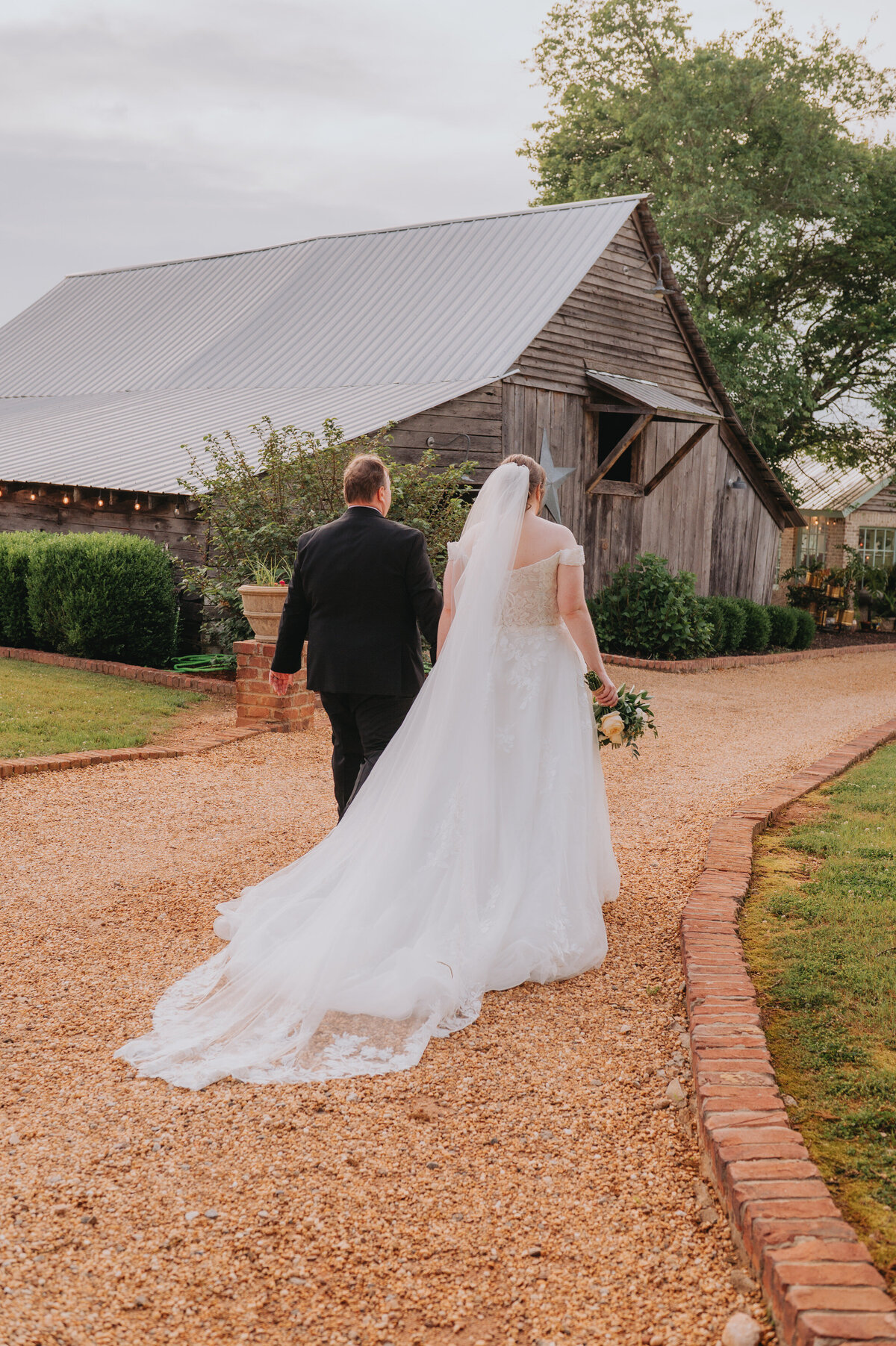 A couple walks away towards a barn
