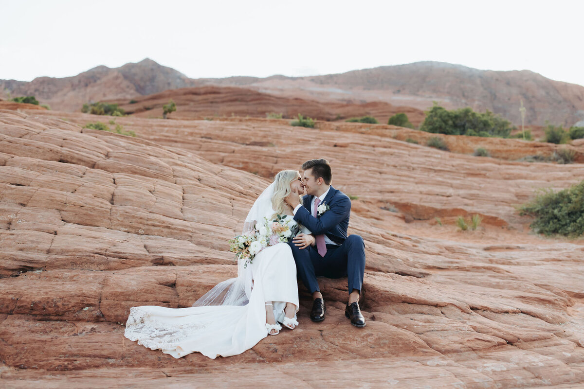 couple embracing on rock by valley