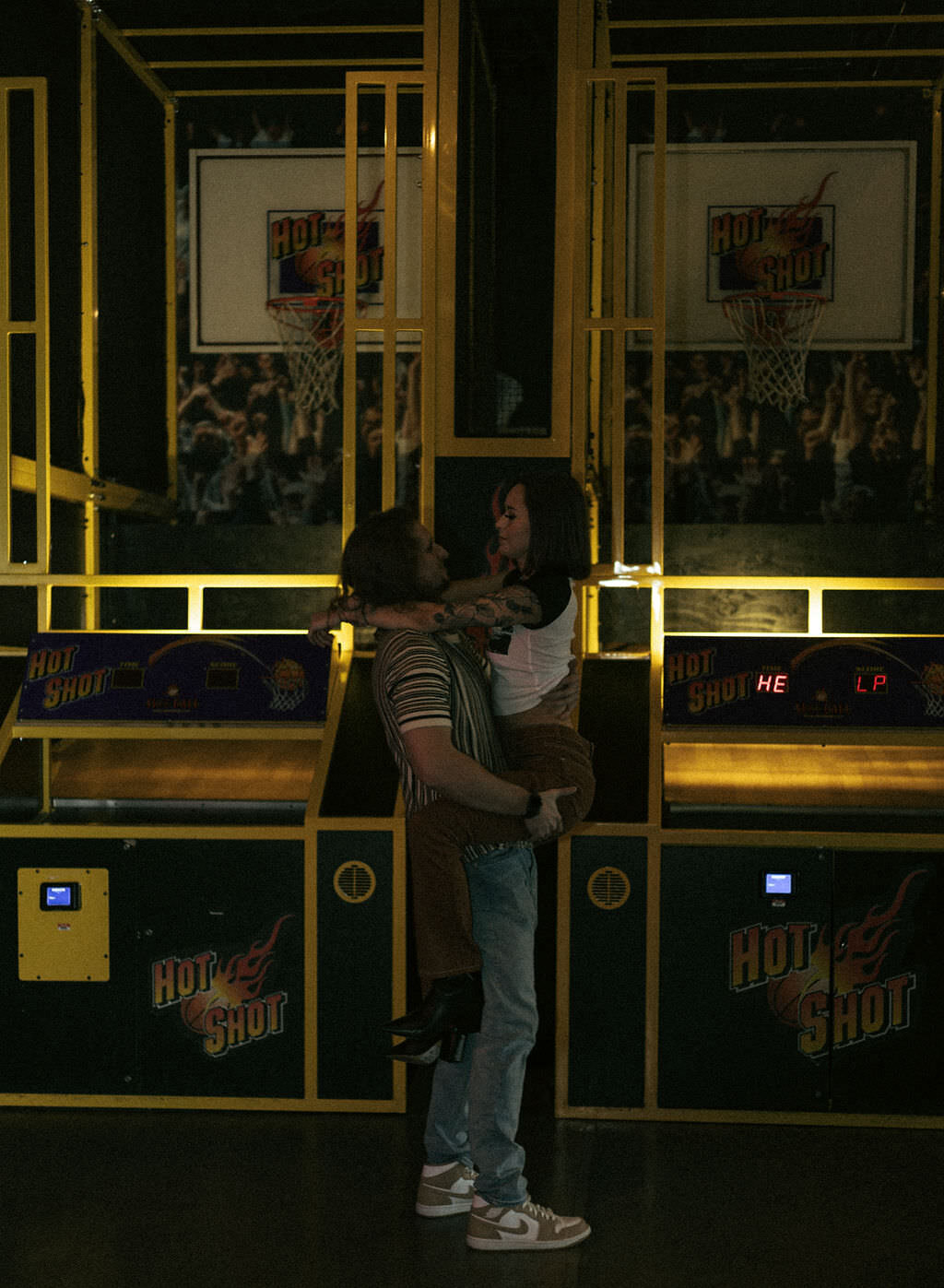 A person holding up their partner at an arcade.