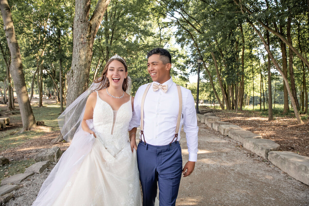 Bride and groom walking on a path in a park laughing