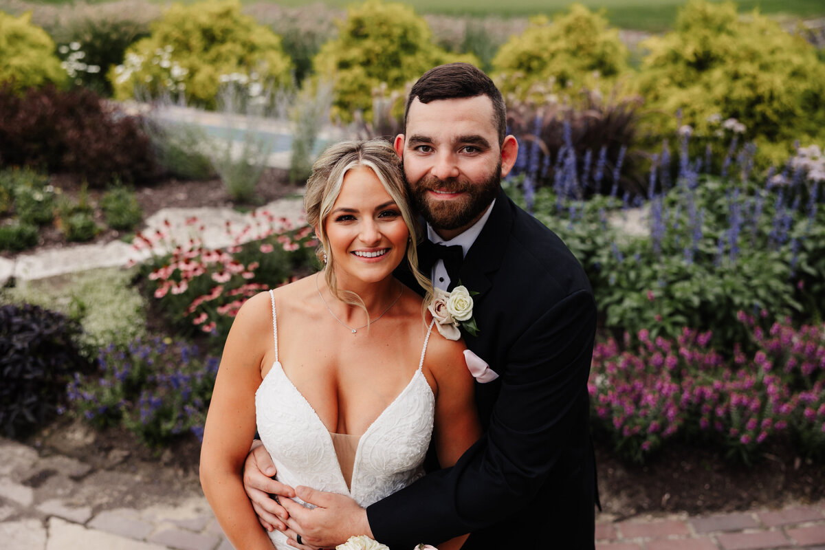 A wedding portrait in front of flowers at Mistwood Golf Club.