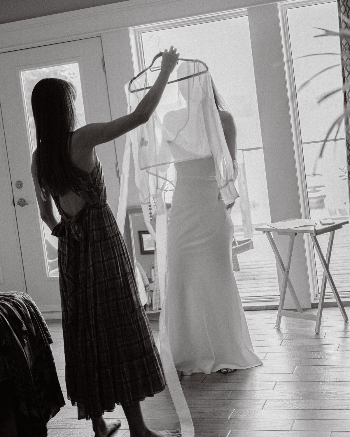 sister holds up the final piece of the dress for  the soon to be wife