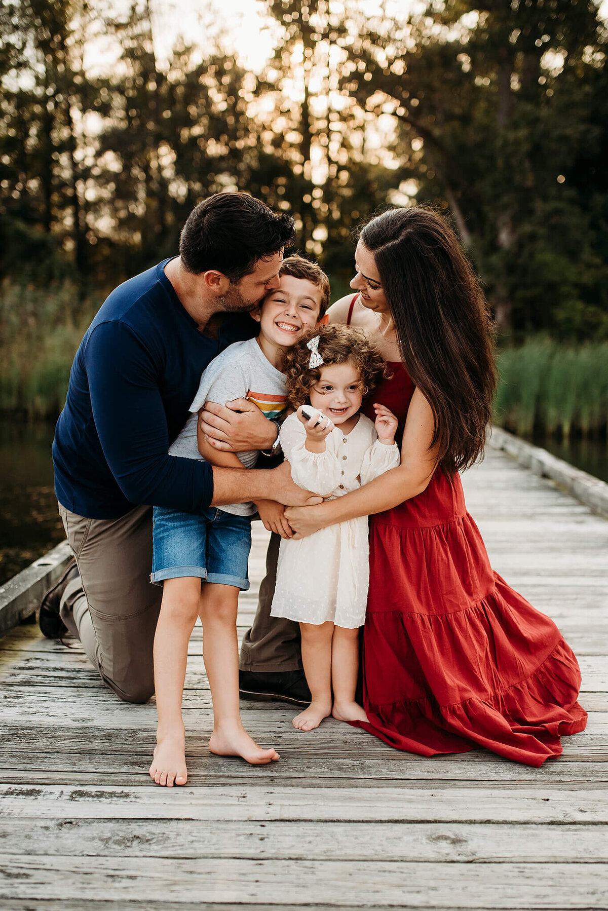 Family with two young children hugging and smiling on a pier Marshy Point Nature Center Baltimore Maryland