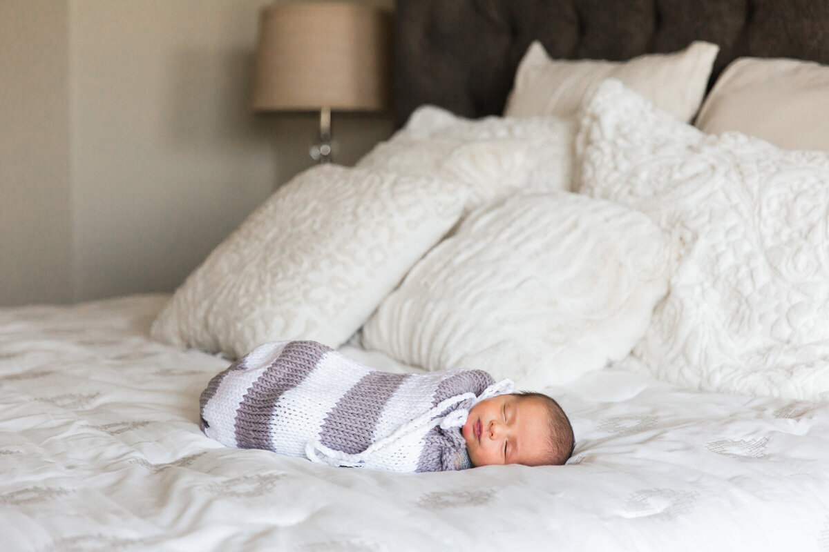 newborn baby sleeping on bed in lifestyle photography session
