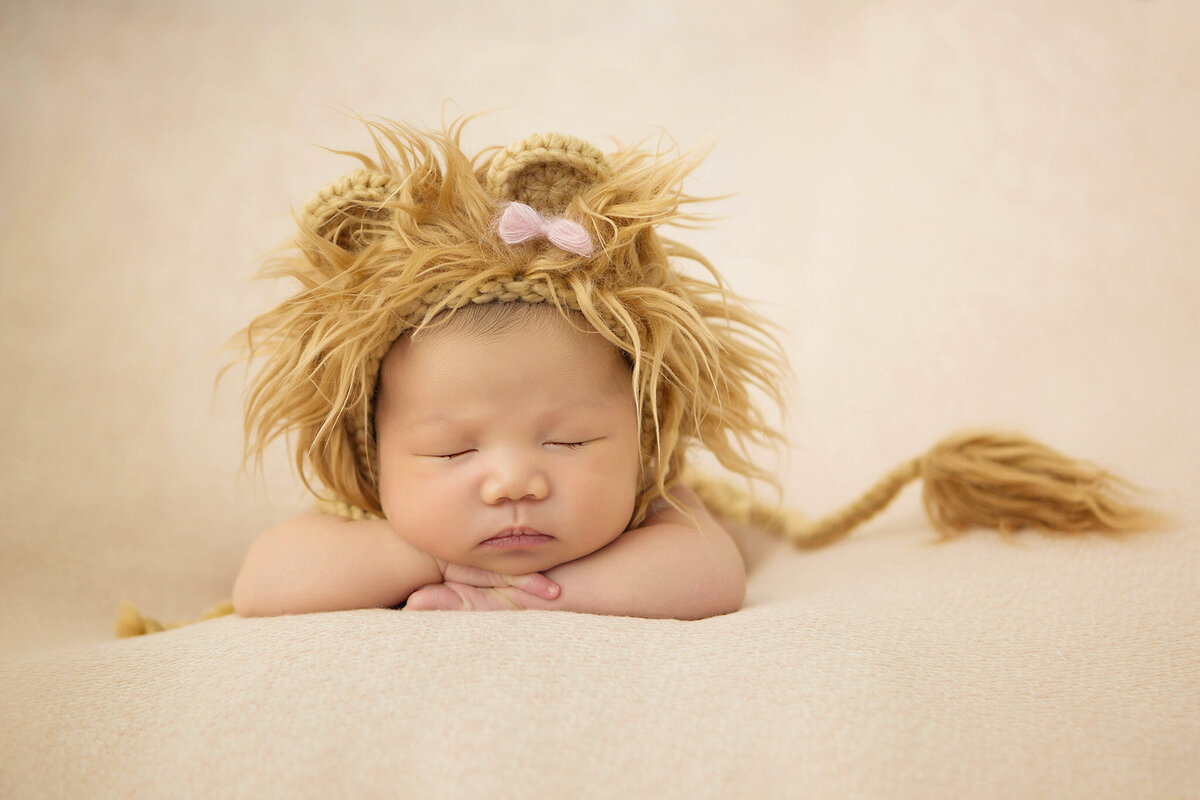 Newborn baby asleep at newborn photoshoot wearing a Lion bonnet taken by Los Angeles newborn photographer