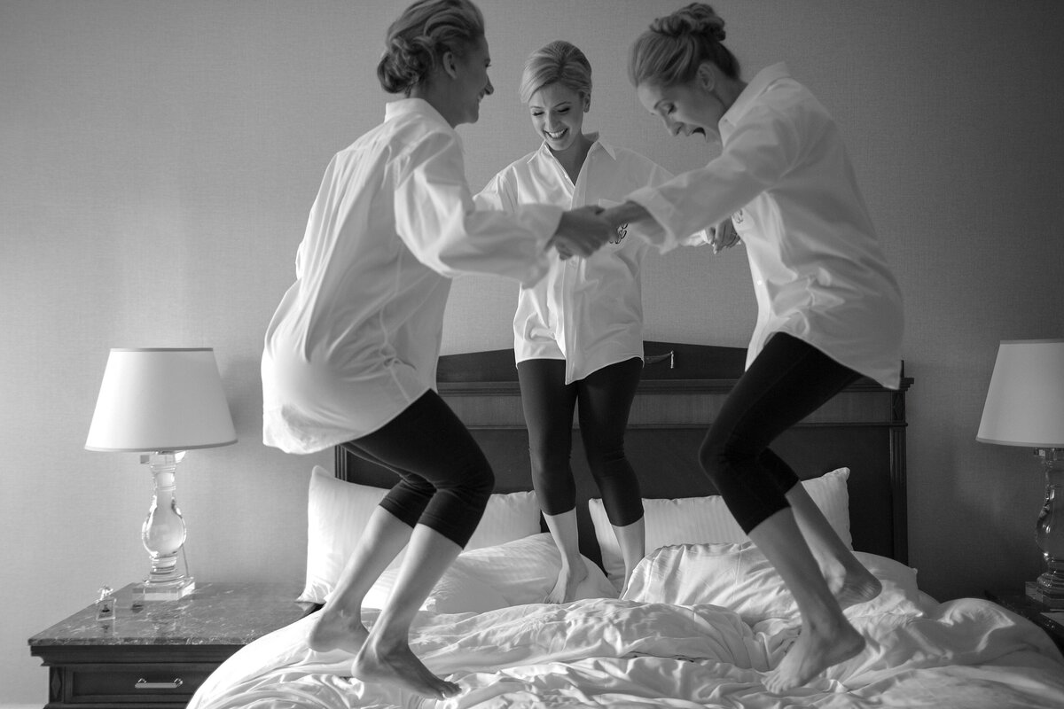 Bride jumps on bed with bridesmaids at Fairmont Copley Plaza.