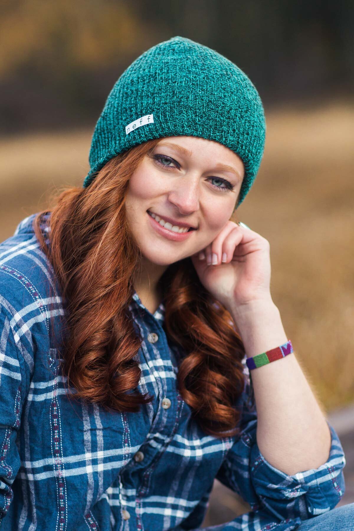 Girl posing for senior pictures wearing a green beanie during autumn at Silver Lake Brighton Utah.