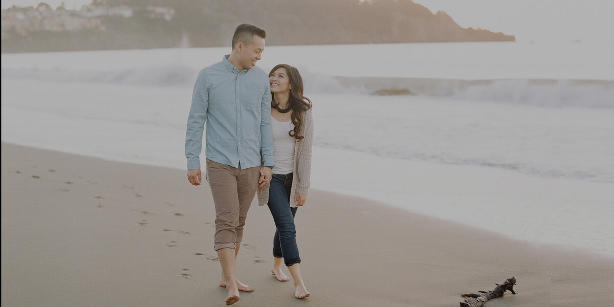 Newly engaged man and his fiancee share a walk together at Baker Beach.
