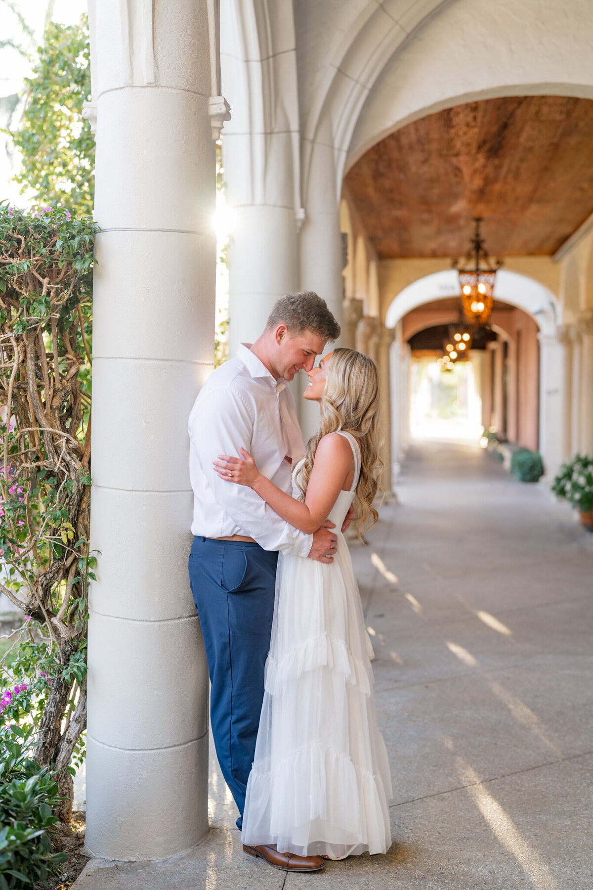 Couple embracing and smiling at one another by columns