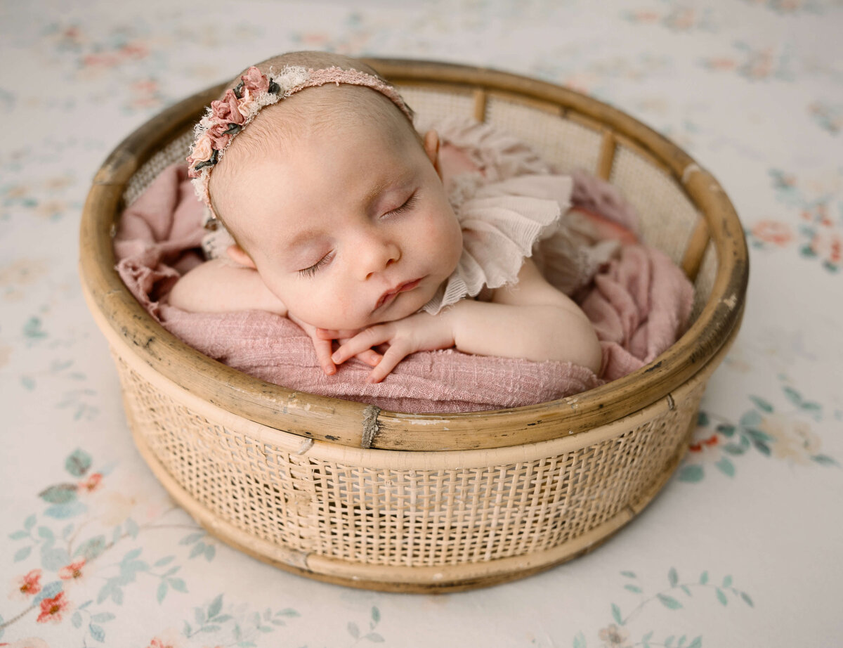 Baby girl laying in a round basket in an Erie pa photography studio