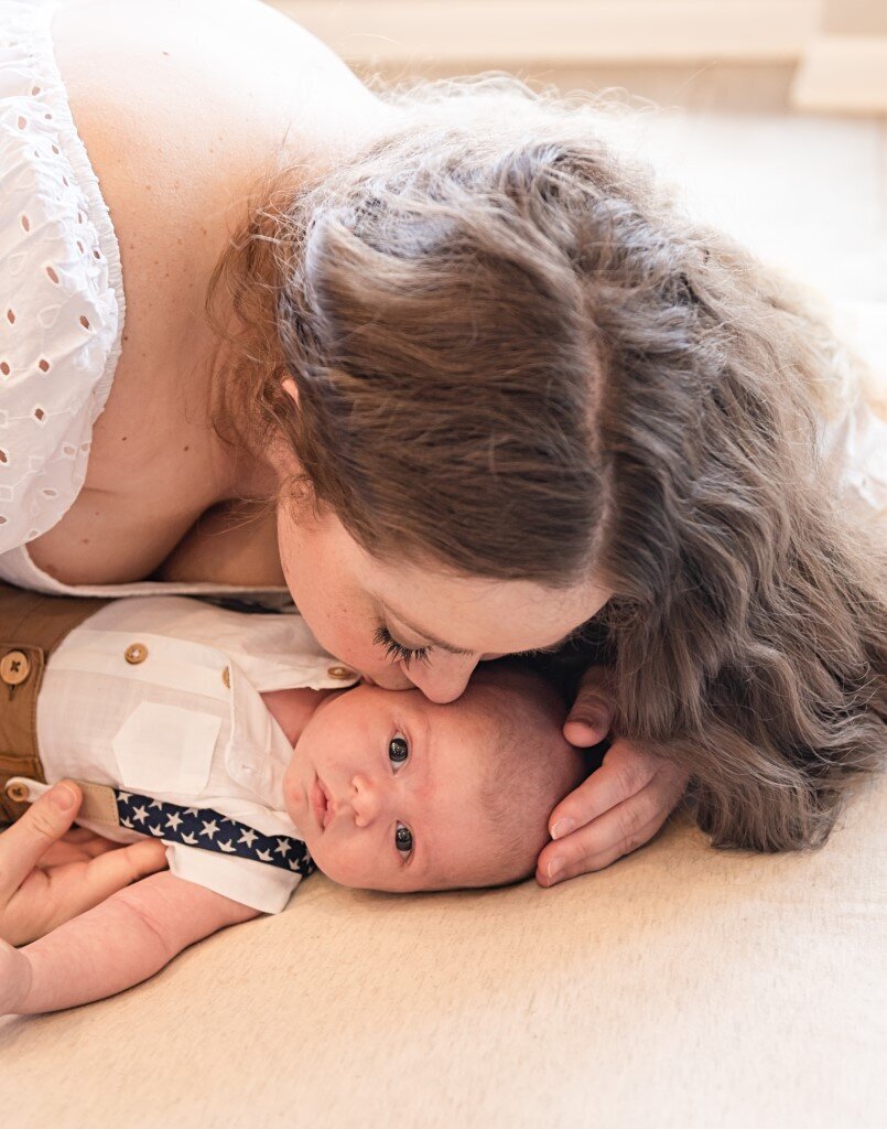 mom leaning down to kiss newborn