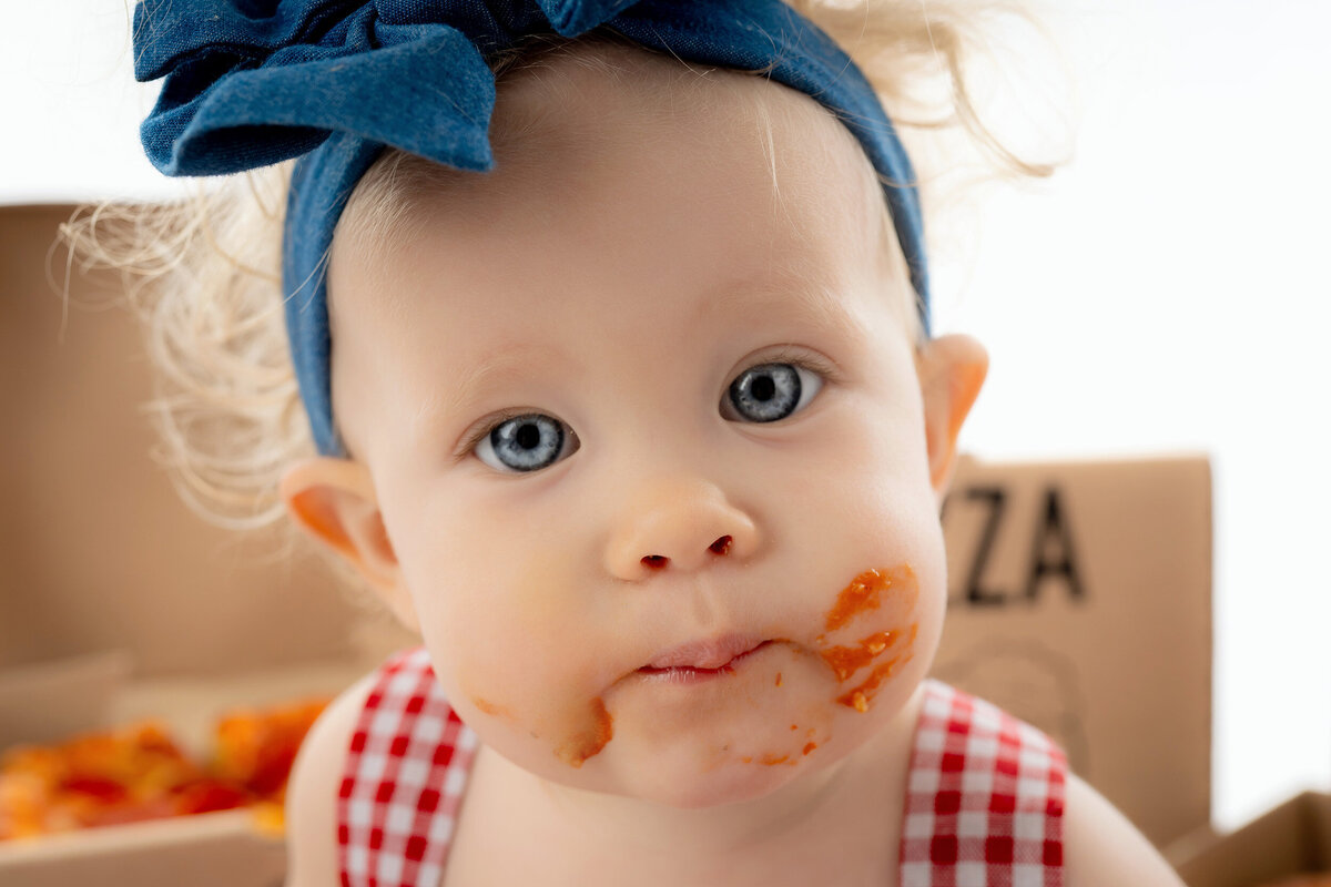 Close up of a baby’s face covered in pizza sauce