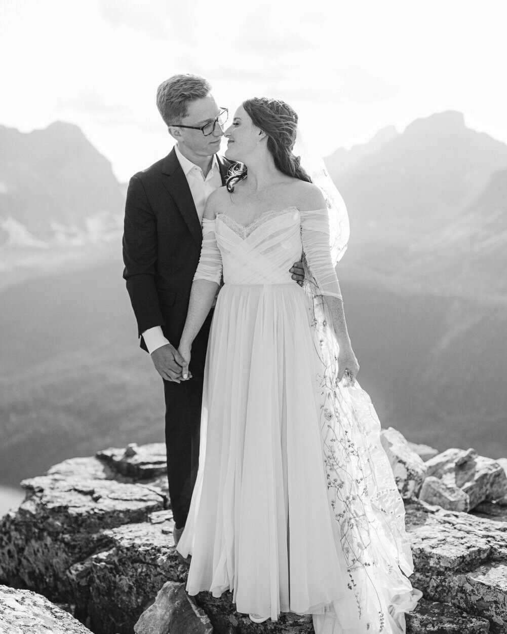 This stunning photograph captures the groom holding his bride at the top of an adventurous hike at the Tower of Babel near Moraine Lake. The dramatic mountain landscape provides a breathtaking backdrop, reflecting the couple's love for adventure and each other on their special day.