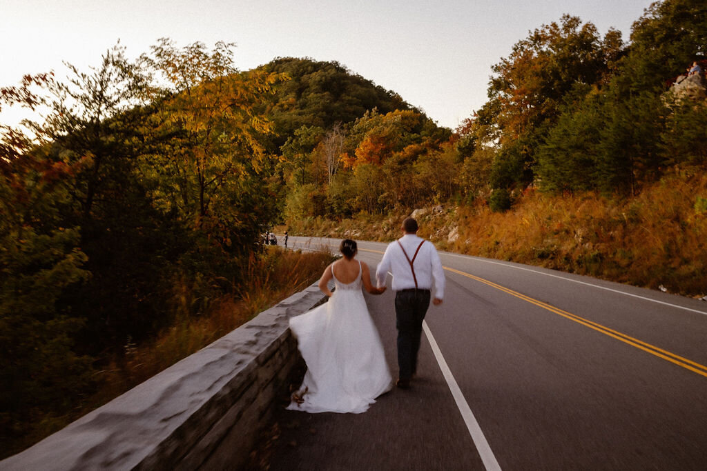 couple elopes to Gatlinburg in the Foothills as they run down the parkway road together at sunset captured by Gatlinburg photographer  