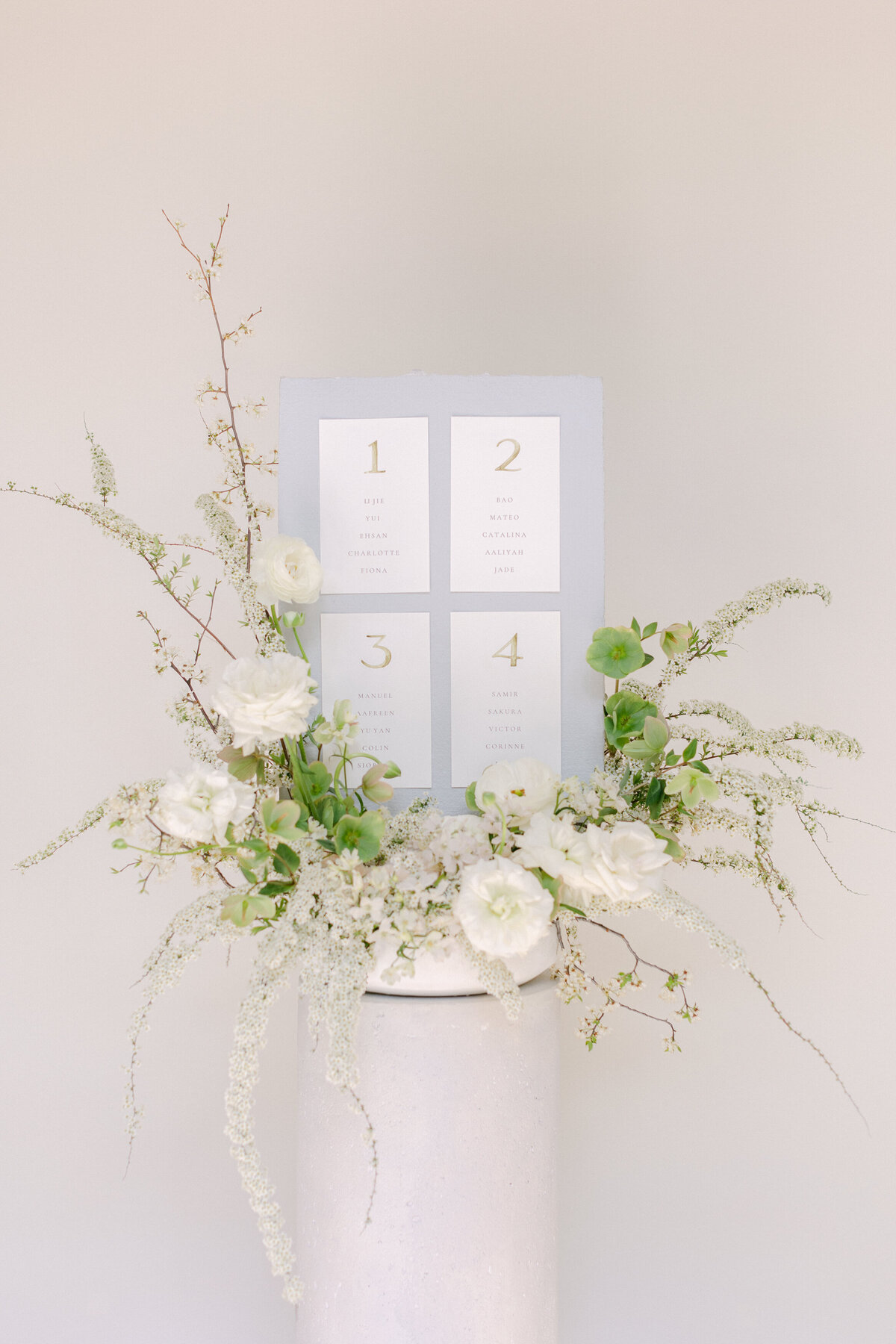 A place card display at a Montreal wedding is decorated with elegant, airy white flowers. 