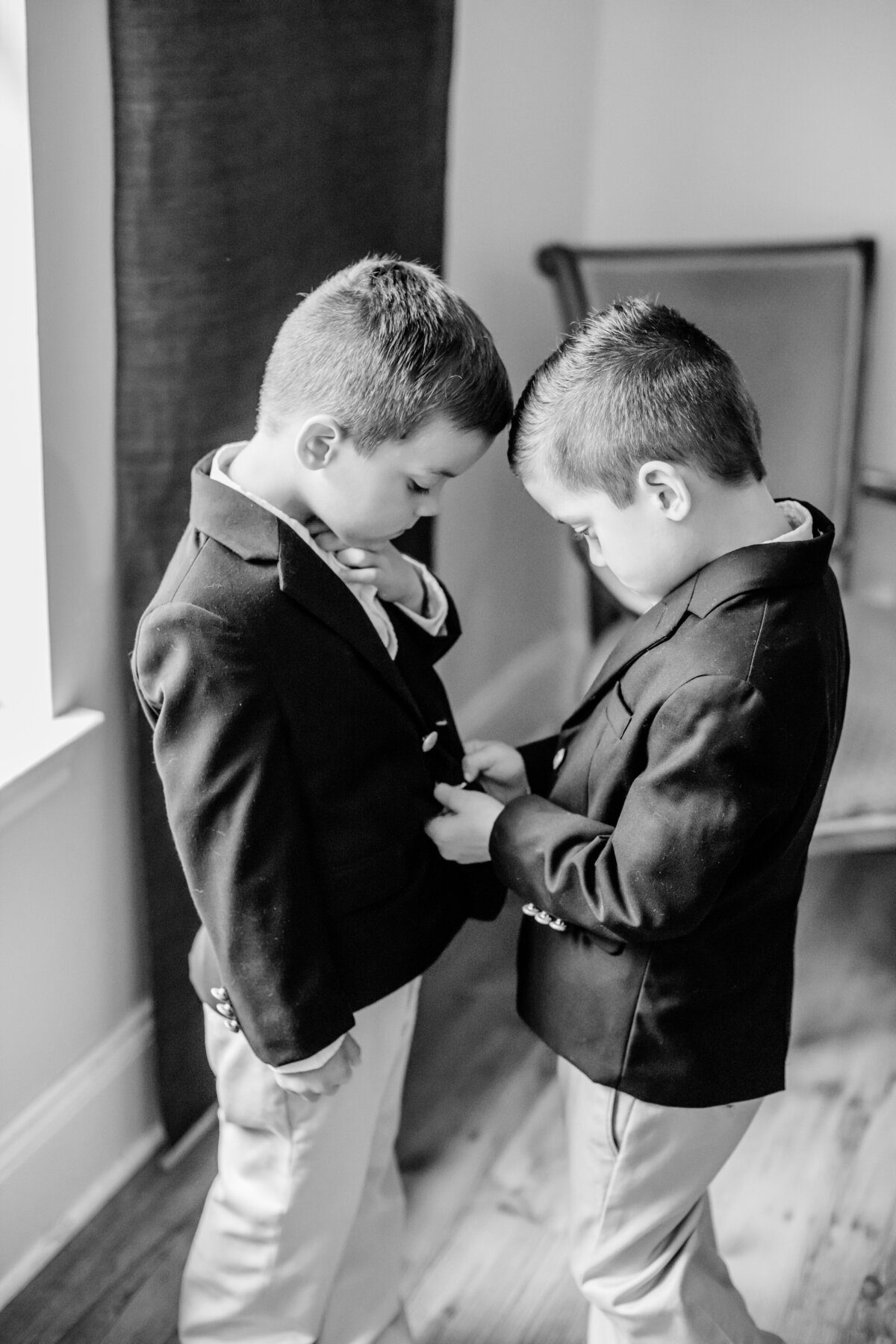 2 young boys help button jackets black and white wedding at Gardens at West Green in San Antonio Texas