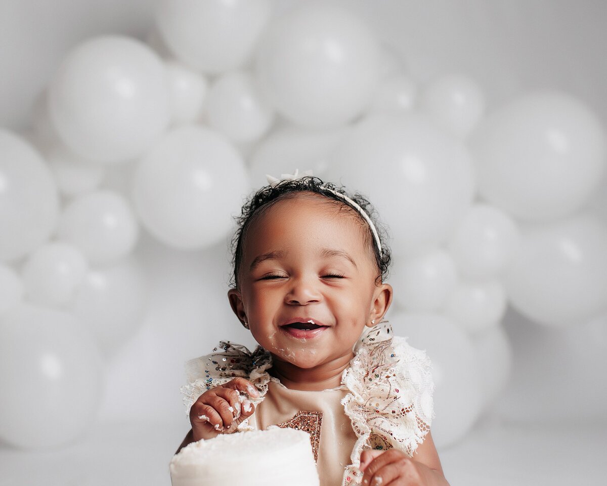 Baby laughing with frosting on face during studio cake smash session