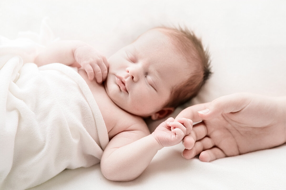 newborn holding moms finger