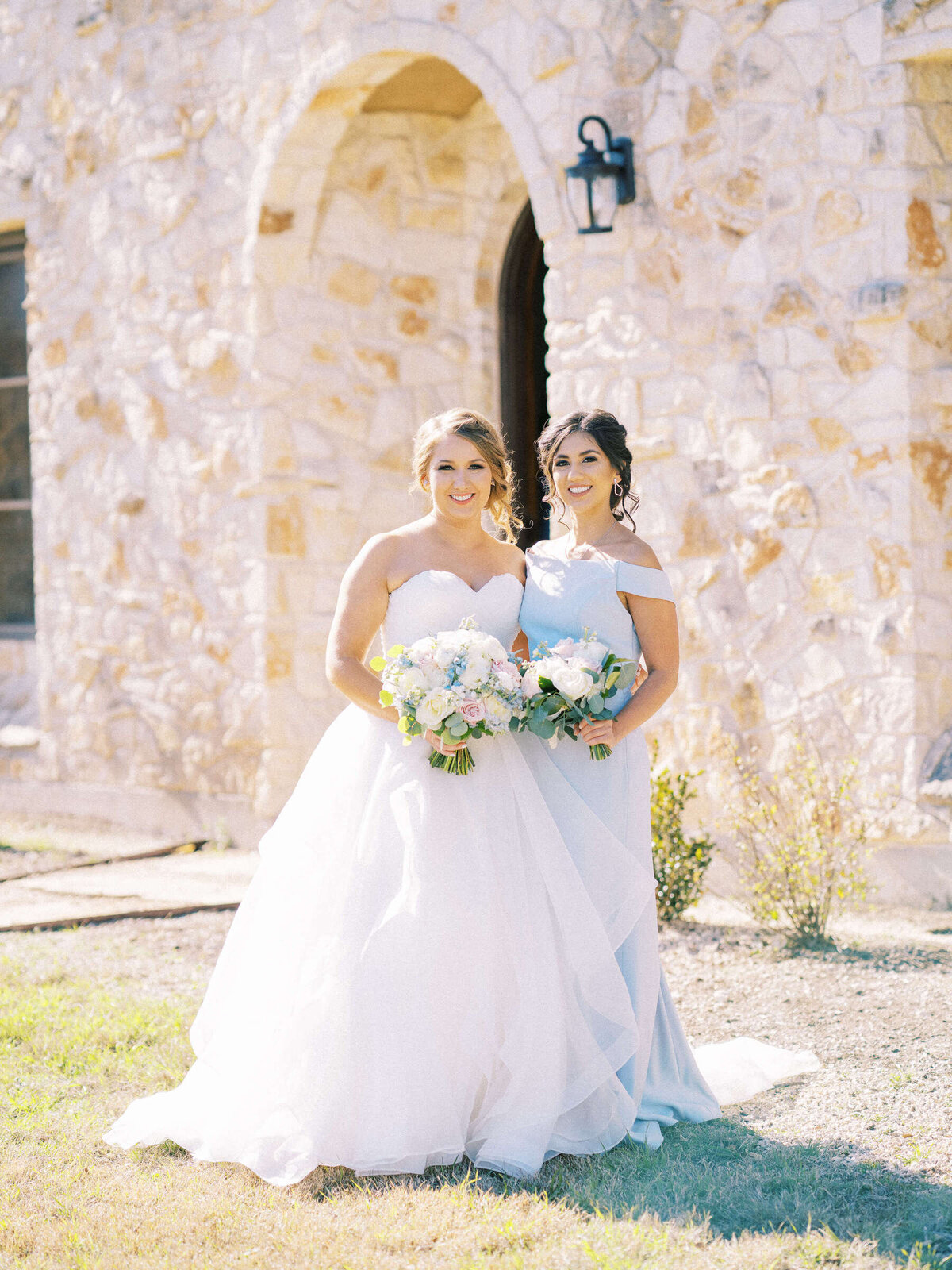 Bride and maid of honor stand outside courtyard at The Vineyard at Florence wedding