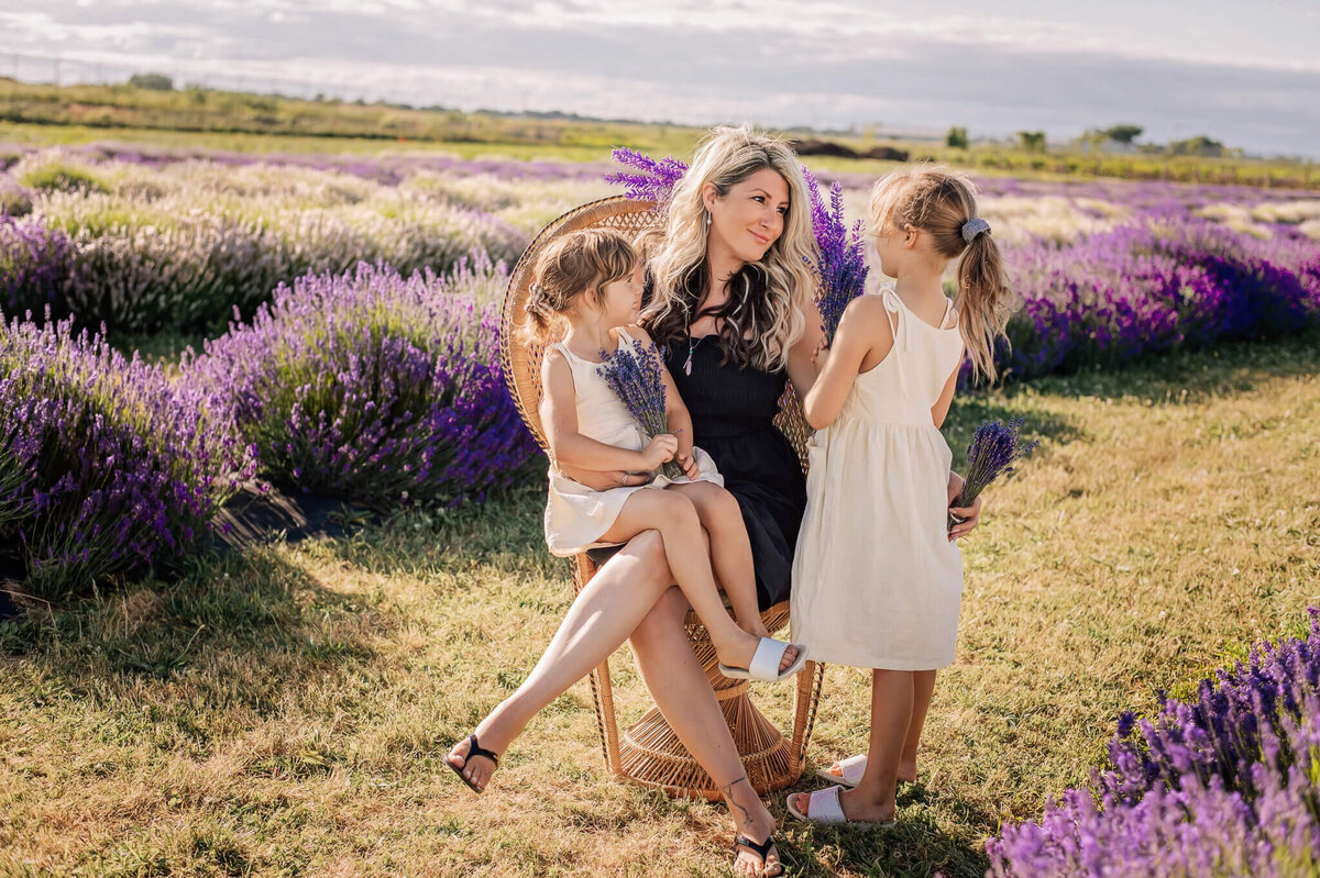 Mom and her daughters sitting in a chair at NEOB Lavender by GTA and Hamilton Family Photographer, Tamara Danielle.
