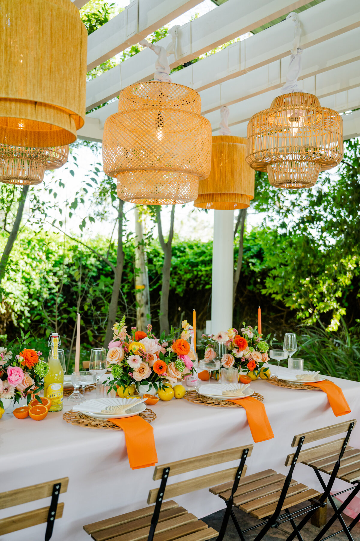 Table decorated with oranges and yellows, accented by hanging lights, at Seven Sycamores for a warm, vibrant atmosphere.