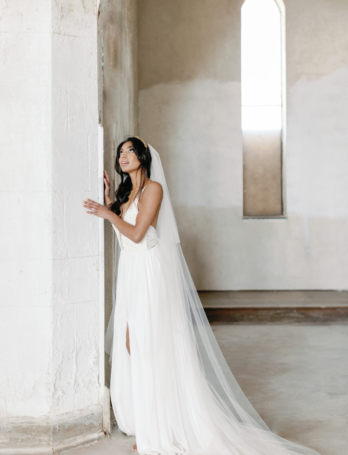 Indian bride in long veil under crumbling arches of abandoned cathedral
