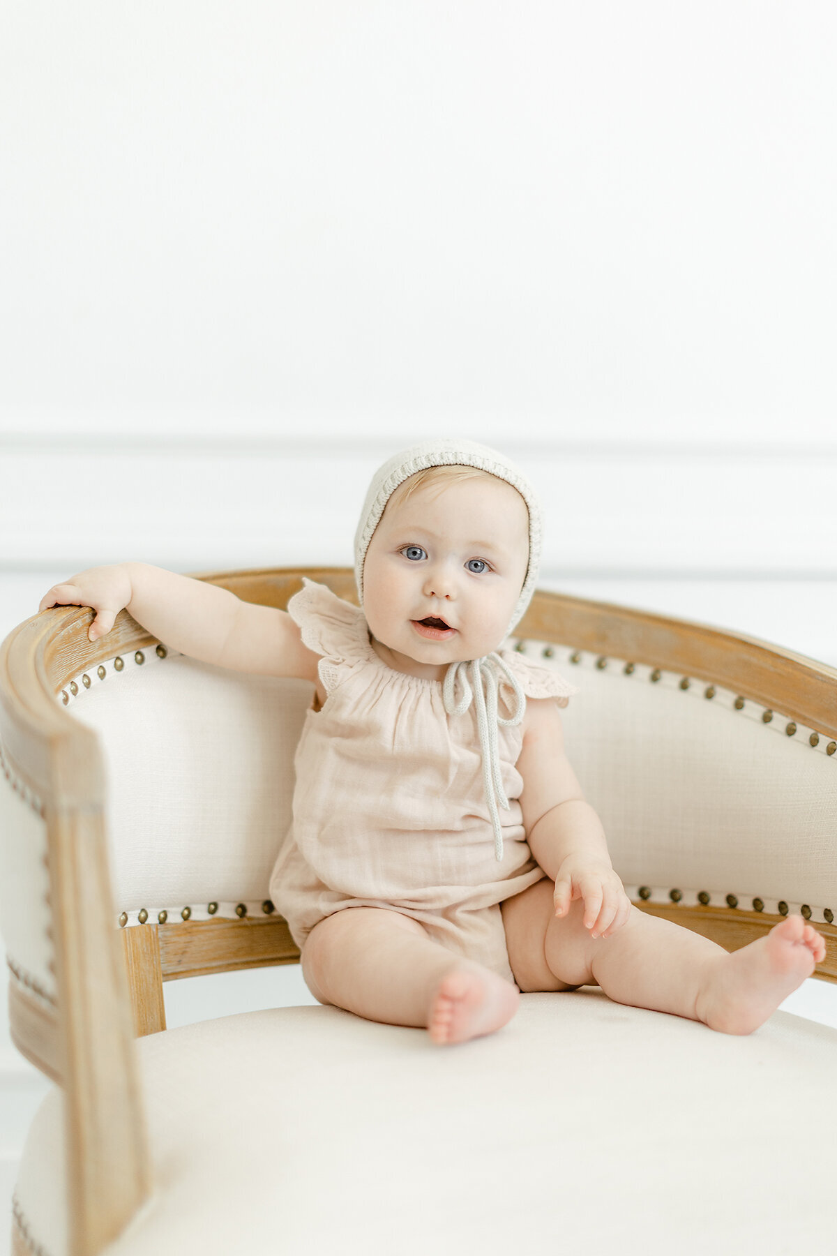 A in studio milestone session of a baby girl sitting on a chair.