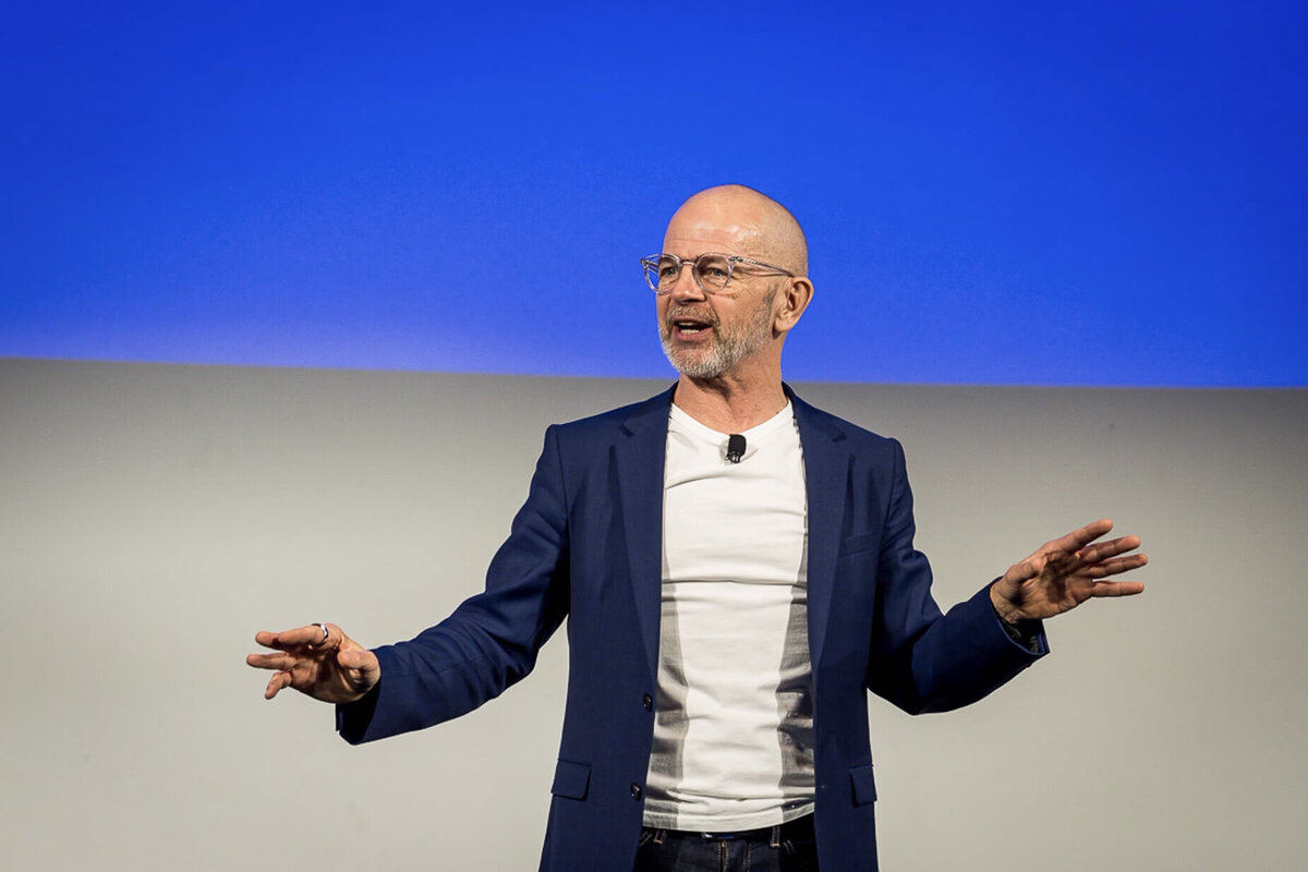 NYC executive portrait of charismatic speaker presenting on stage with blue backdrop
