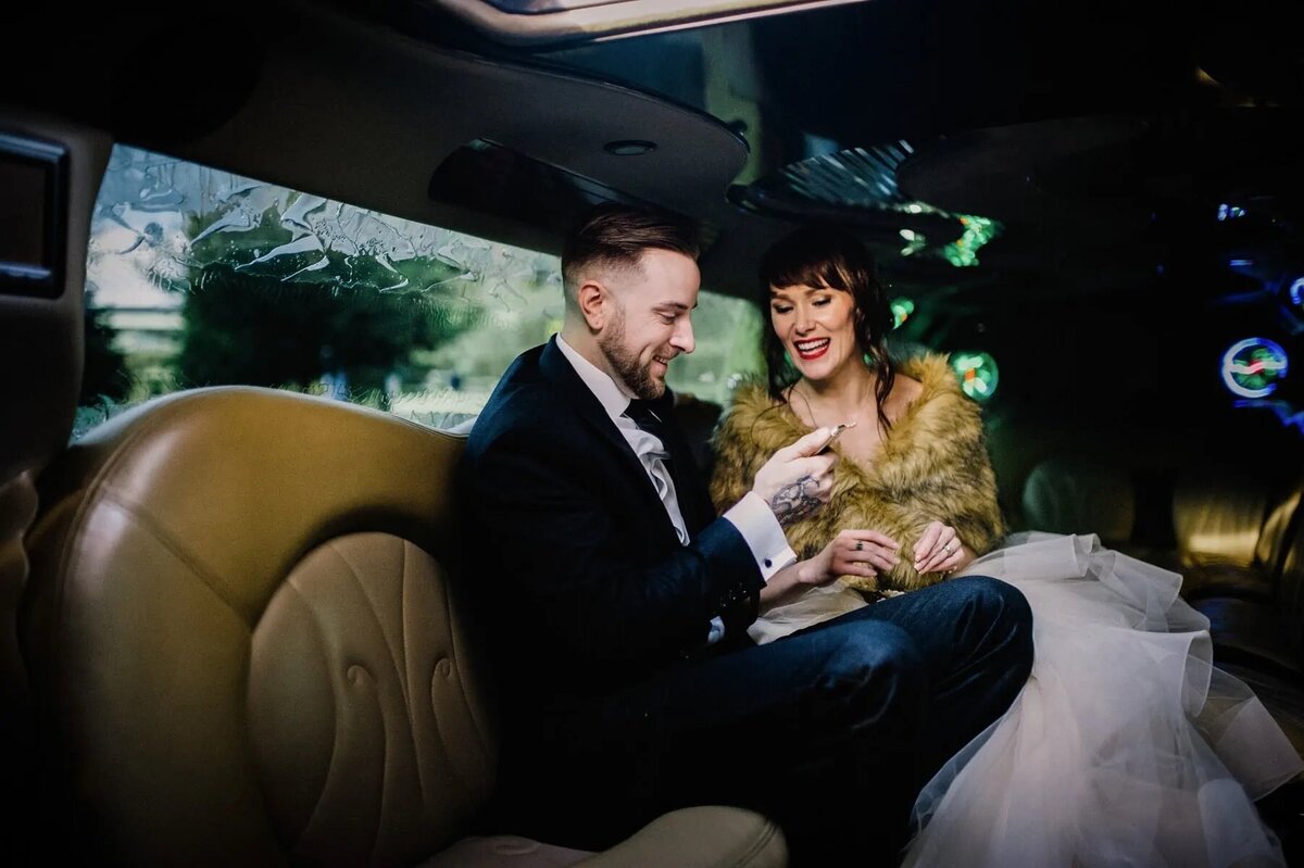 A bride and groom sitting in the back of a limo.