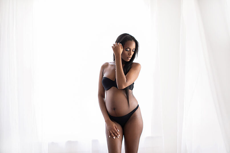 Black pregnant mom in black bikini posing in white studio