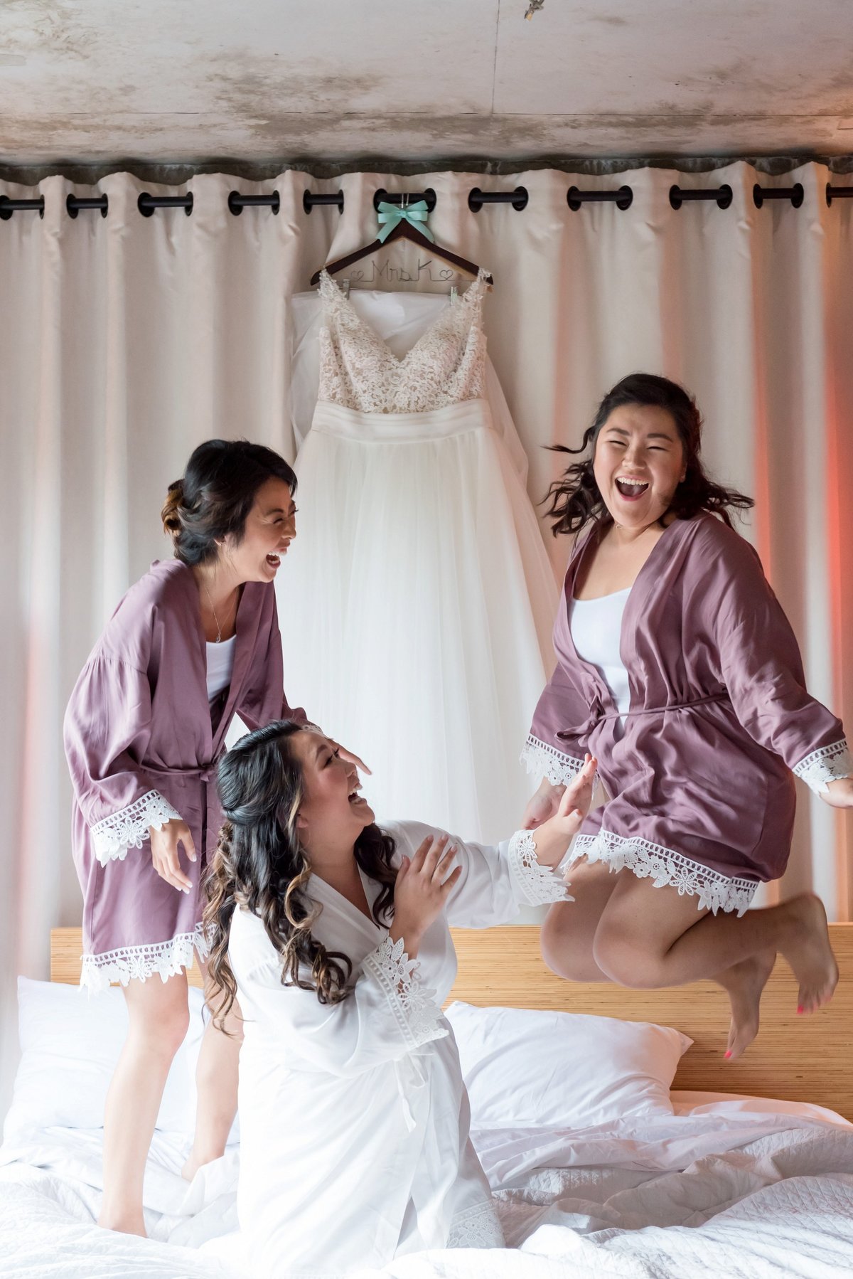 bride and bridesmaids jumping on bed