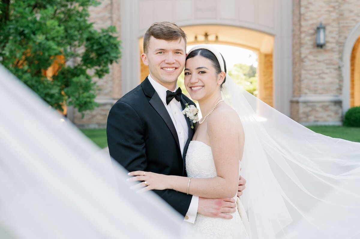bride and groom embracing while wrapped in bride's veil