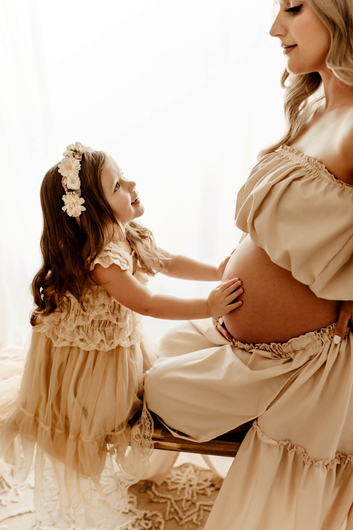 Little girl looks up at her mother while having her hands placed on her mother's belly, Yukon maternity  photos.