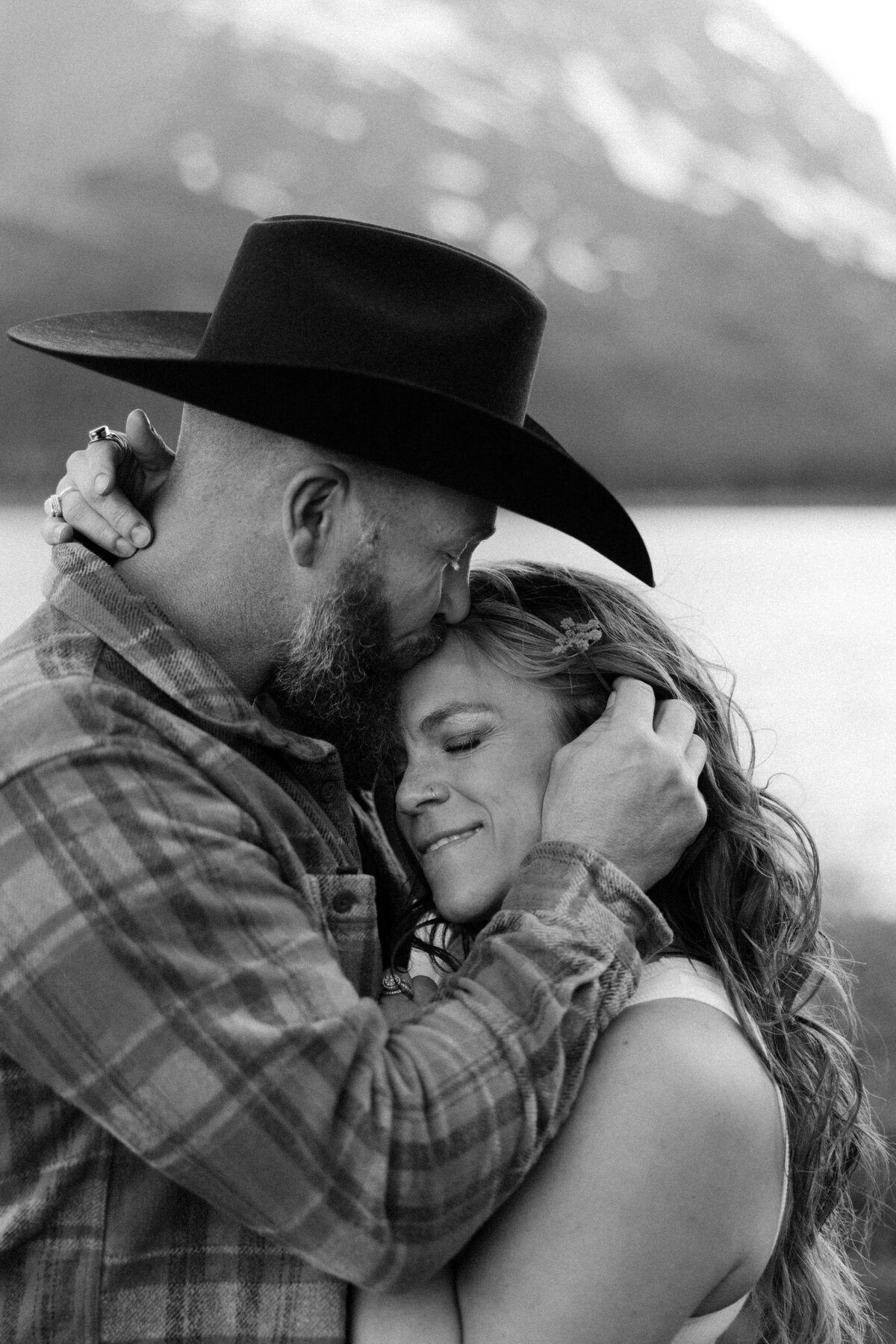Black and white image of a man in a cowboy hat kissing his partner.