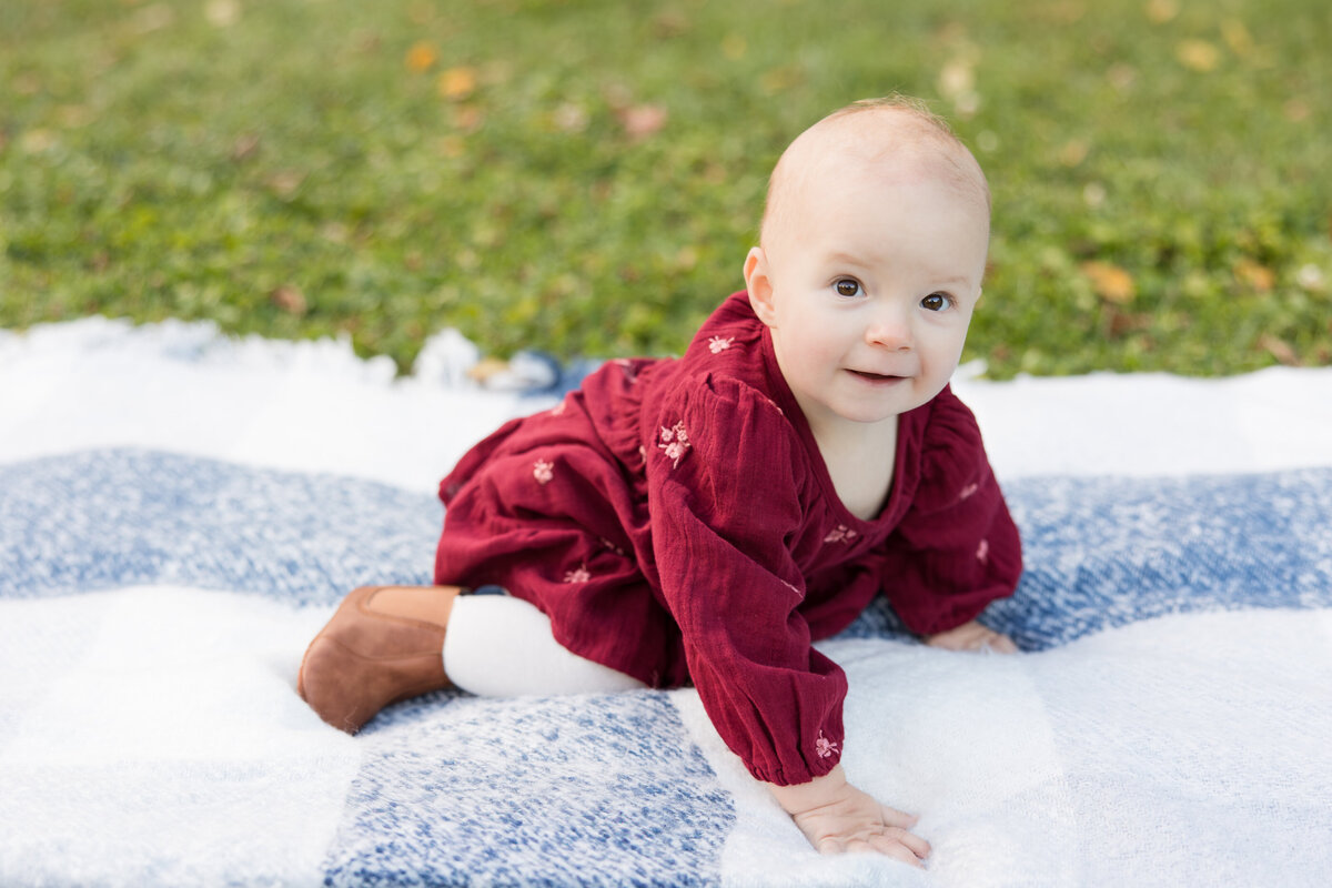 A baby girl in a red dress on a white and blue blanket